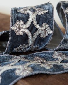 a pair of blue velvet ribbons with silver sequins on them sitting on top of a wooden table