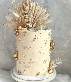 a white cake with gold decorations and feathers on it's side, sitting on a table