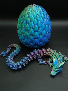 two blue and one green dragon figurines sitting next to each other on a black surface