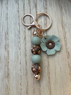 a close up of a key chain on a table with a flower and beads attached to it