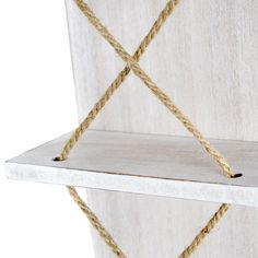 a white shelf with rope on it and a wooden wall hanging from the back side