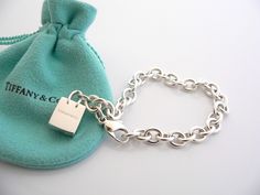 Overview: Here is a gift that she will surely adore! It is shiny, stylish, and super versatile! This piece will make someone REALLY happy! :) Offered for sale is a wonderful Tiffany & Co. Sterling Silver Signature Shopping Bag Charm Bracelet. Hanging from its bright Tiffany silver chain is a very pretty Shopping Bag charm with the words "Tiffany & Co" on it! A classic Tiffany piece that any girl will adore! Very pretty and just an adorable piece! It is simple, elegant, and classic all rolled int Luxury Bracelets With Logo Charm As Gift, Elegant Bracelets With Logo Charm For Gift, Elegant Bracelets With Logo Charm As Gift, Palladium Hardware Jewelry As Gift, Designer Rectangular Bracelets As Gift, Luxury Rectangular Bracelet Gift, Luxury Rectangular Bracelet As Gift, Palladium Hardware Bracelets As Gift, Silver Bracelets With Logo Charm For Gift