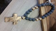 a rosary with a cross on it sitting on top of a wooden table next to a small beaded necklace