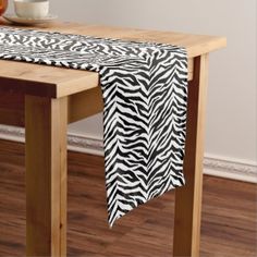 a black and white table runner on top of a wooden table with a coffee cup