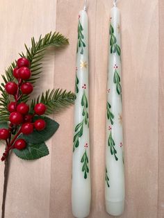 two candles decorated with holly and red berries