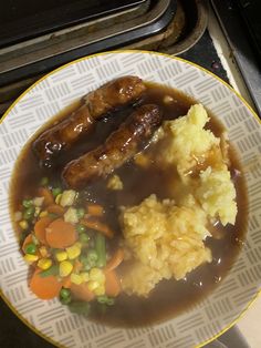 a white plate topped with meat and veggies on top of mashed potatoes