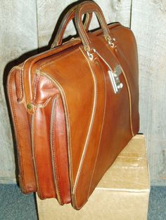 Classic ,Top Open,Valise style ,briefcase made from top quality USA tanned bridle leather.Also sometimes refered to as a Lawyers Briefcase,this beautiful, but rugged case measures approx 16.5x14x6 inches. It's in stock in black with chrome hardware or brown with solid brass hardware, and keyed lock.It has 2 dividers inside, making 3 equal sized compartments.Other colors and sizes available on special order. Like all our products, it's created one at a time in Montana, USA, using only the best ma Lawyer Briefcase, Black With Chrome, Carryon Bag, Montana Usa, Lock It, Comfortable Jeans, Phone Holster, Chrome Hardware, Leather Briefcase