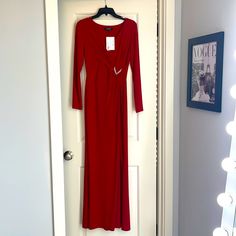 a red dress hanging on a white door in front of a mirror with a light behind it