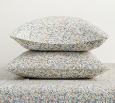 three pillows stacked on top of each other in front of a white wall with blue and yellow flowers