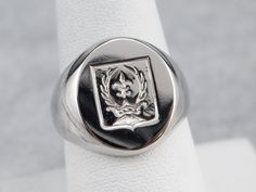 This signet ring is heavy and impressive! Crafted of luxurious platinum, this ring depicts a fleur de lis, crown, and laurel wreath emblem that is carved with great detail. Please note that this signet ring has its original monogram, and unfortunately, this piece cannot be altered without affecting the quality of the piece. Please feel free to contact us to help you find your perfect signet ring in your style and budget! Metal: Platinum Top Measurements: 14 x 16 mm, Oval Ring Size: 8 Marks: "PLA Classic Coat Of Arms Ring, Classic Polished Signet Ring For Commemoration, Classic Formal Rings With Coat Of Arms, Classic Signet Ring With Coat Of Arms For Anniversary, Formal Signet Ring With Coat Of Arms, Classic Signet Ring For Commemoration, Luxury Signet Ring With Coat Of Arms For Anniversary, Classic White Gold Rings For Commemoration, Luxury Engraved Signet Ring For Commemoration