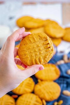 a hand holding a peanut butter cookie in front of some cookies on a blue plate