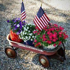 an old wheelbarrow with flowers and american flags