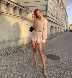 a woman is walking down the street with her hand on her head and wearing sandals