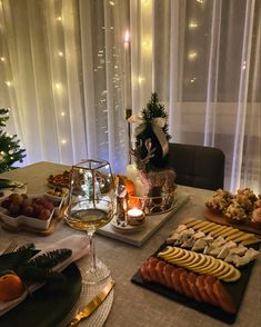 a table topped with food and drinks next to a window covered in sheer curtained drapes