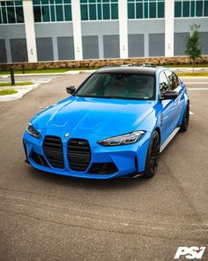 a blue sports car parked in an empty parking lot next to a large office building