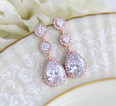 "Swarovski Pure Brilliance Cubic Zirconia rose gold bridal earrings feature pave framed rounds which dangle into a brilliant pear-shaped drop. These beautiful earrings are created in genuine Rose Gold plating and they're sure to look glamorous on brides looking for blush gold jewelry to accessorize their wedding gowns. Earrings measure 1-7/8\" Matching necklace: https://www.etsy.com/listing/273127374/bridal-backdrop-necklace-rose-gold-back?ref=shop_home_active_1 Matching bracelet: https://www.et Wedding Bridal Earrings In Rose Gold With Halo Design, Rose Gold Halo Bridal Earrings For Wedding, Wedding Dangle Earrings With Halo Setting, Wedding Halo Setting Dangle Earrings, Rose Gold Halo Setting Earrings For Wedding, Rose Gold Round Wedding Earrings, Gold Dangle Earrings Wedding, Bridal Earrings Rose Gold, Rose Gold Dangle Earrings