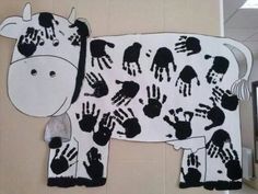 a cow made out of handprints on the side of a wall with a mirror behind it