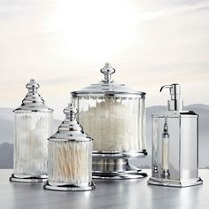 three glass containers with soap dispensers next to each other on a table