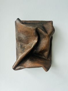 a bronze sculpture on a white wall in the shape of an elephant's head