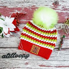 a knitted hat with a pom - pom sits on top of a wooden table