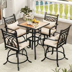 an outdoor dining table with four chairs and a small wooden table on top of a white rug