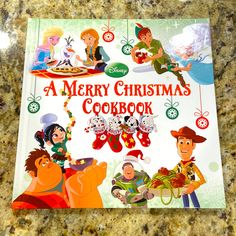 a merry christmas cookbook sitting on top of a granite countertop with cartoon characters