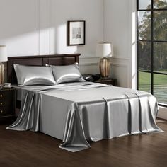 a bed with silver sheets and pillows in a room