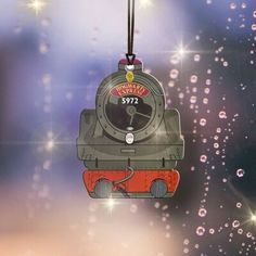 a train ornament hanging from a string with water droplets on it's surface