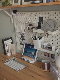 a wooden desk topped with a computer monitor next to a shelf filled with books and other items