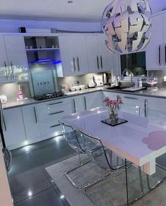 a modern kitchen with white cabinets and stainless steel counter tops is lit up by blue lights