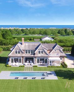 an aerial view of a large house with a pool in the foreground and ocean in the background