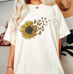 This is a DTG printed graphic t-shirt of a vibrant sunflower morphing into butterflies. It's perfect for summer and fall when sunflowers bloom! The sunflower butterfly shirt shown here is natural cotton and is printed many ink colors. The ink is embedded into the fabric and will last for years when cared for properly.  Butterflies Sunflower Shirt, Comfort Colors Shirt for Women, Sunflower Gifts, Butterfly Lover Tshirt, Sunflower Tee The Comfort Colors C1717 100% Ring Spun Cotton T-Shirt is very appropriately-named. All colors are inspired by nature and have a perfect lived-in, weathered look. Shirts are sent through a unique dyeing process that makes them incredibly soft and long-lasting. Each piece is soft-washed 50 times before making its way to you! Stitched at the collar, armhole, slee Yellow T-shirt With Sunflower Design For Spring, Cute Butterfly Print T-shirt For Spring, Summer Casual T-shirt With Sunflower Print, Cotton Crew Neck T-shirt With Sunflower Design, Yellow Printed T-shirt For Fall, Cute Summer T-shirt With Butterfly Print, Cute Butterfly Print Summer T-shirt, Cute Butterfly Print T-shirt For Summer, Cotton Short Sleeve T-shirt With Sunflower Print