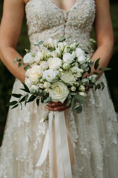 a bride holding a bouquet of white flowers