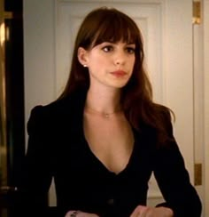 a woman in a black suit is looking at the camera