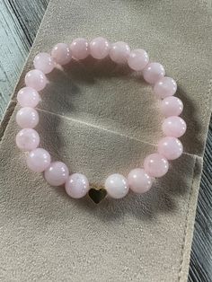 "Made with 8mm round Madagascar Rose Quartz beads on stretch cord and a gold played heart shaped accent bead.  Size-7 inches. If you need a larger bracelet please leave a note in the checkout letting me know the length desired. I am happy to customize the size at no additional charge. (I.E. Hi! Can you make this bracelet for me 8 inches long.)  When I choose stones I seek them based on what speaks to my heart. It is my hope that those who need this stone, will find it.   Here are some notes Rose Quartz:     * Properties: Known as the \"Stone of Love,\" rose quartz is associated with love, compassion, and emotional healing.     * Usage: Ideal for promoting self-love, attracting love into one's life, and fostering harmonious relationships." Elegant Round Beads Stretch Bracelet For Valentine's Day, Heart-shaped Stretch Bracelet With 8mm Beads As Gift, Elegant Heart-shaped Bracelets With 8mm Beads, Elegant Heart-shaped 8mm Beads Bracelet, Valentine's Day Heart Beads Stretch Bracelet, Pink Heart-shaped Spiritual Beaded Bracelets, Heart Shaped 8mm Beads Bracelet As Gift, Heart Shaped 8mm Beads Bracelet Gift, Heart-shaped Bracelet With 8mm Beads As Gift