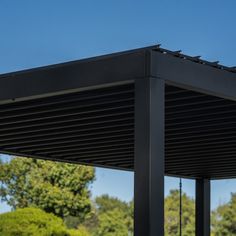 the top of a black metal structure with trees in the backgroud and blue sky