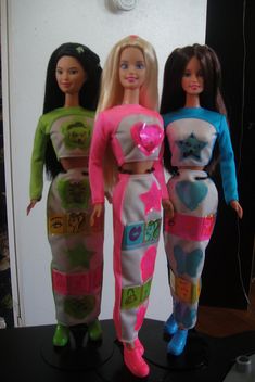 three barbie dolls standing next to each other