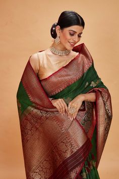 Look your ethnic best on special occasions in this green tussar Banarasi saree with maroon zari border. It has an antique zari red pallu and zari creeper. The saree comes with a matching blouse piece. Disclaimer: The shown stitched blouse on the model is for display purpose only. The saree comes with a matching blouse piece and finished with fall and piko. Banarasi Sari, Tussar Silk Sarees, Indian Clothing Store, Fashion Journals, Tussar Silk Saree, Banarasi Saree, Indian Clothing, Traditional Fabric, Banarasi Sarees