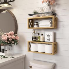 two wooden shelves holding toiletries and towels in a bathroom with flowers on the counter