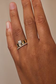 a woman's hand with a gold and white diamond ring on top of it