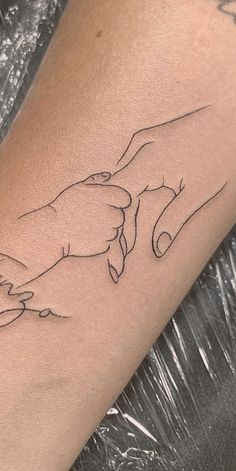 a tattoo on the arm of a woman with two hands holding each other's fingers