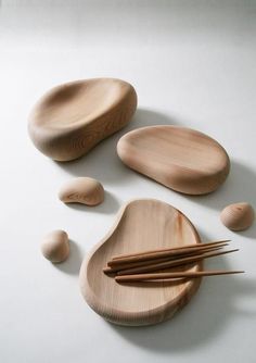 three wooden spoons and two chopsticks on a white surface