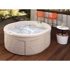 a hot tub sitting on top of a wooden deck next to two chairs and tables