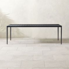 a black table sitting on top of a white tiled floor next to a planter