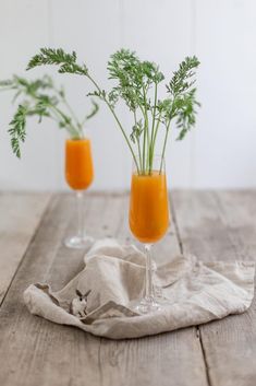 two glasses filled with orange juice and garnished with parsley on a wooden table