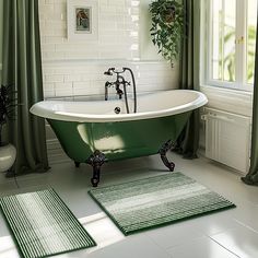 a green bathtub and rugs in a white bathroom