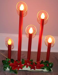 lighted candles with poinsettis and holly on them