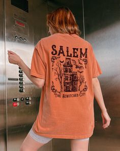 Comfort Colors® Salem Massachusetts shirt, Salem Witchy Haunted House shirt for her, Witch Tshirt, Halloween Party T-shirt Vintage Fall Tee These are Unisex Garment-Dyed T-shirt made 100% with ring-spun cotton. Shirts look retro and vintage. The soft-washed, garment-dyed fabric brings extra coziness to your wardrobe while the relaxed fit makes it an excellent daily choice. FEATURES - Medium fabric (6.1 oz/yd² (206.8 g/m - Relaxed fit - Sewn-in twill label - 100% ring-spun cotton - Without side seams - Garment-dyed fabric - Double needle stitching on all seams Sizing * Please refer to the size chart in the listing photographs to determine your size. * If you are not sure what size to order, you can measure a shirt you already own to see what size would fit you best. Our shirts are measured Spooky Orange Crew Neck Top, Spooky Short Sleeve Shirt With Letter Print, Spooky Relaxed Fit Screen Print T-shirt, Spooky Screen Print Relaxed Fit T-shirt, Spooky Crew Neck Shirt With Letter Print, Halloween Themed Relaxed Fit Shirt With Letter Print, Halloween Fitted Top With Sublimation Print, Spooky Cotton Shirt With Screen Print, Halloween Relaxed Fit T-shirt With Letter Print