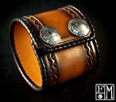 a leather cuff with two silver coins on it