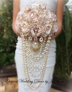 a woman wearing a white dress holding a bouquet with pearls and flowers on it's belt